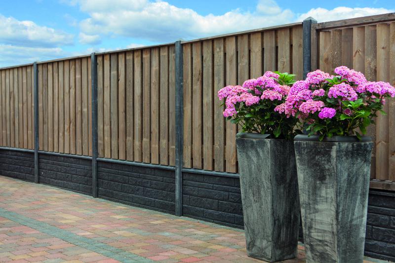Houtbetonschutting met bloemen ervoor.